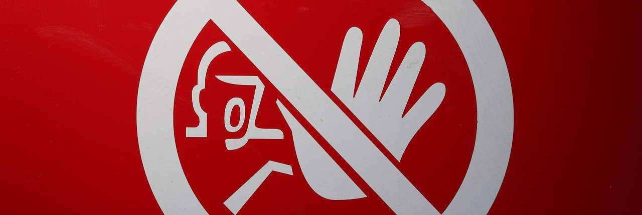 A wide image of a red sign with a white circle featuring a symbol of a hand being blocked by a diagonal bar, indicating a warning against entry or a prohibition of access.
