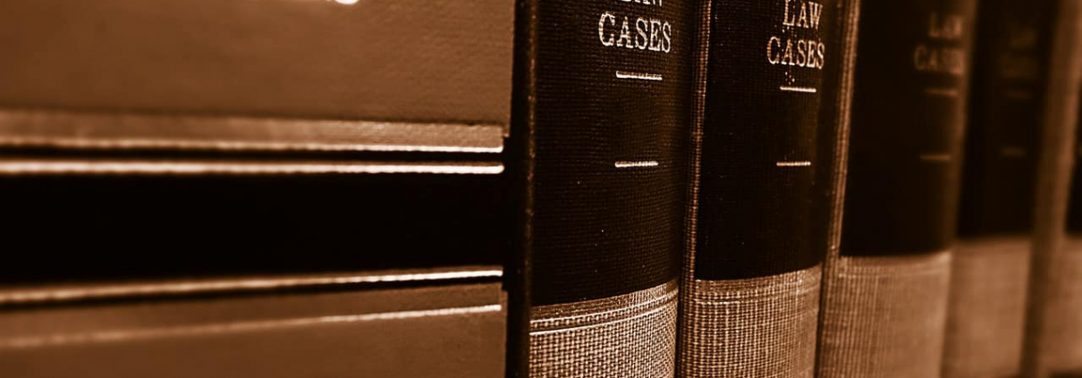 A sepia-toned close-up image of a row of thick books with "LAW CASES" printed on their spines, suggesting a library or study setting with a focus on legal texts.