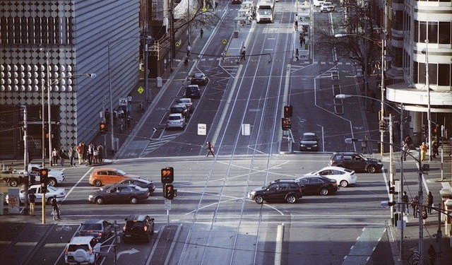A birds-eye view of a busy street intersection with vehicles and pedestrians, highlighting the organized chaos of city traffic.