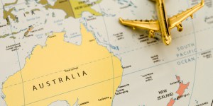 A small golden airplane model positioned on a world map, with a focus on the continent of Australia highlighted in yellow.