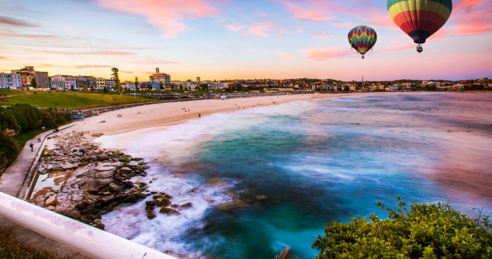 A picturesque landscape with a hot air balloon over a tranquil lake at sunset.