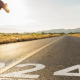 A person sprinting on a road with "2024" painted on the surface, indicating the year, with an early morning or late afternoon rural landscape in the background, featuring a clear sky and distant mountains.