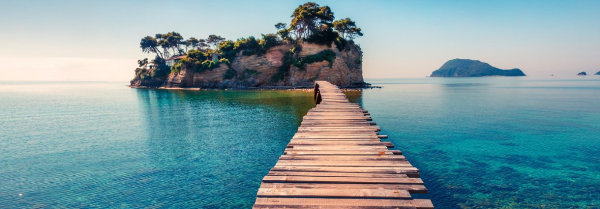 A wood plank bridge stretching from shore to a small tropical island