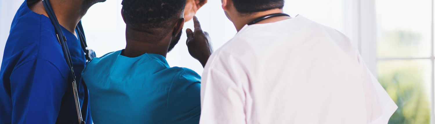 Three medical staff look at and discuss an x-ray